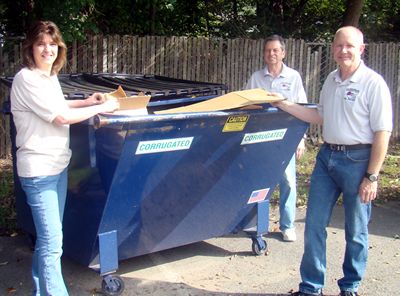 Image of Donna Ricker, Patrick Milligan and David Knizhnik, three industrious employees of the Parsippany Public Library, stand by the container for corrugated cardboard.